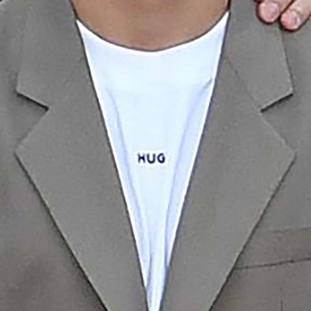 A close-up of one of the men's shirts. It's a white t-shirt and in small black print, there is the word 