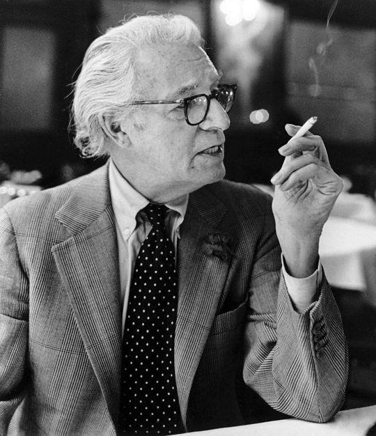 George Frazier is wearing a Russell check suit with a button-down collar shirt. His tie is worn with a four-in-hand knot. 