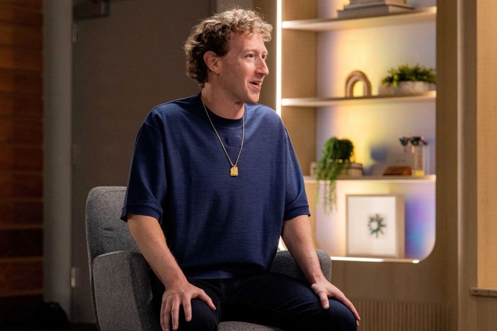 Mark Zuckerberg wearing a blue 3/4th sleeve t-shirt with dark jeans and a gold chain. 