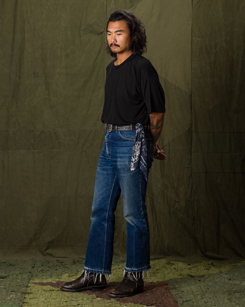 Man wearing raw denim jeans with a raw hem and black t-shirt. 