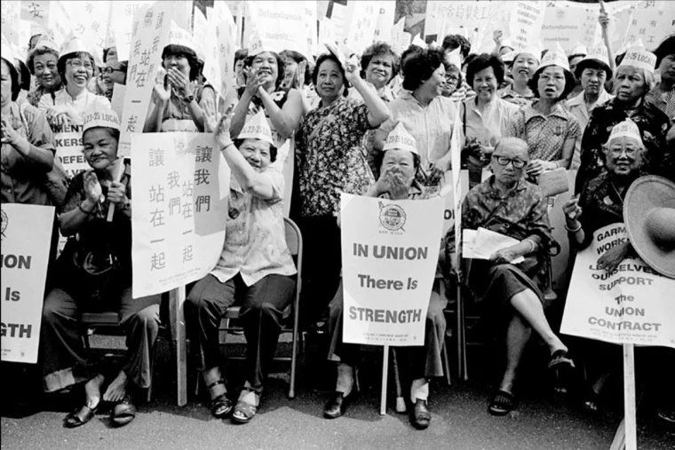 A photo of the 1982 garment workers' strike in NYC Chinatown. A bunch of women are gathered together holding placards that say things like "In Union There is Strength." They were also demanding better wages. 