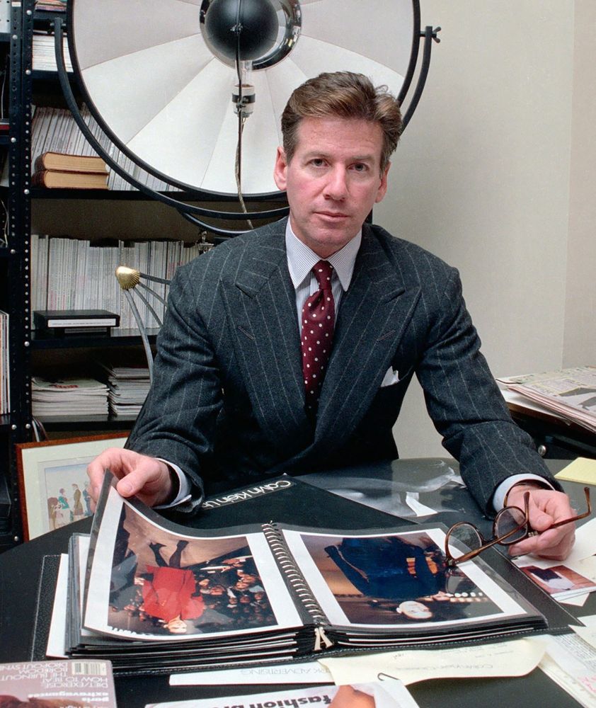Calvin Klein is wearing a grey chalk-striped double-breasted flannel suit with a white shirt. His tie is worn with a four-in-hand knot. 