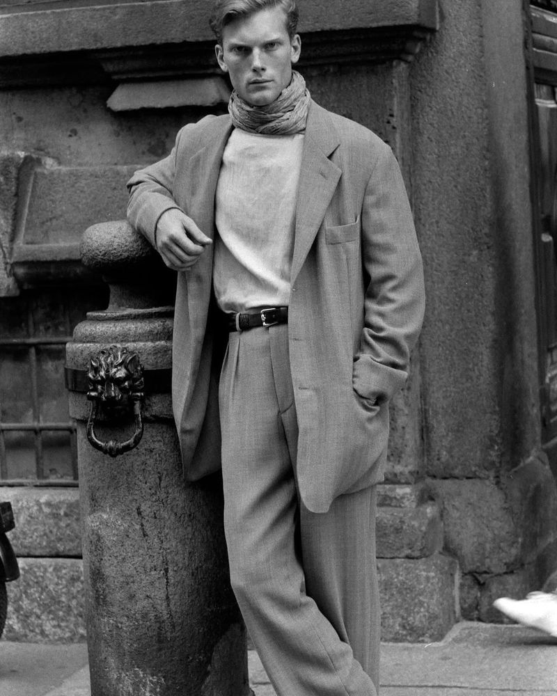 A man in a big mid-gray single-breasted suit wit notch lapels and a scarf. 