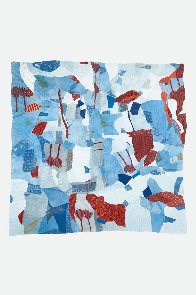 Kantha quilt involving various shades and hues of blue along with red. The motif shows flowers among the patchwork. 