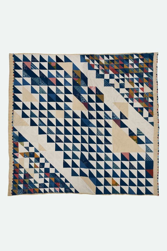 Kantha quilt involving various shades and hues of blue, red, and white. The motif is made up of various triangles. 