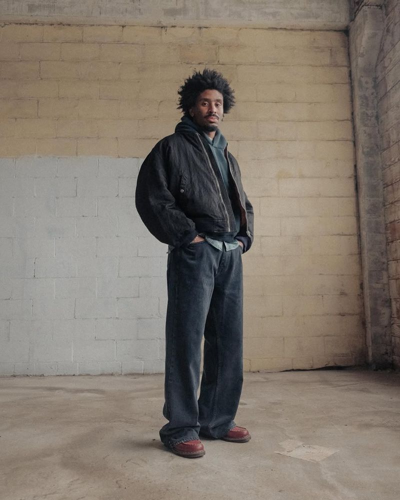 Man wearing pre-washed black jeans with a black jacket. 