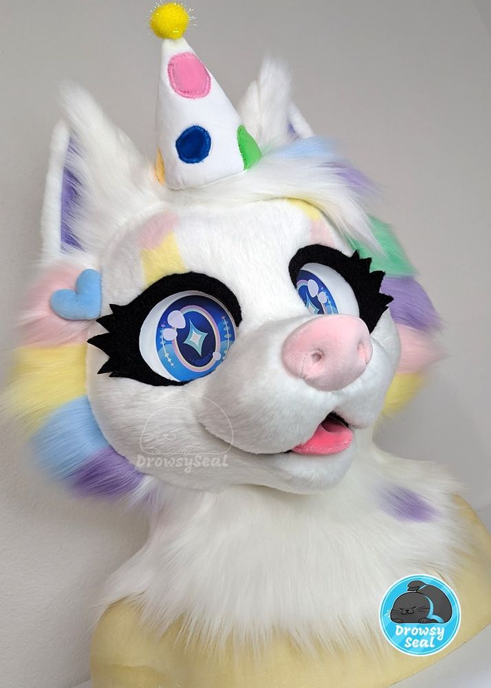 White canine fursuit with multicolor pastel spotting and a spotted party hat 