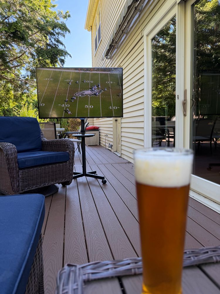 Philadelphia Eagles game on outside television on deck. Beer glass  