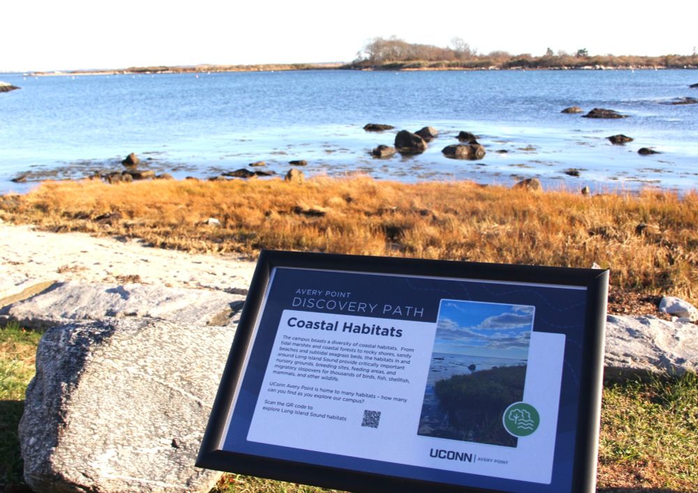 Sign for Avery Point Discovery Path with information about coastal habitats and view of marsh and Long Island Sound
