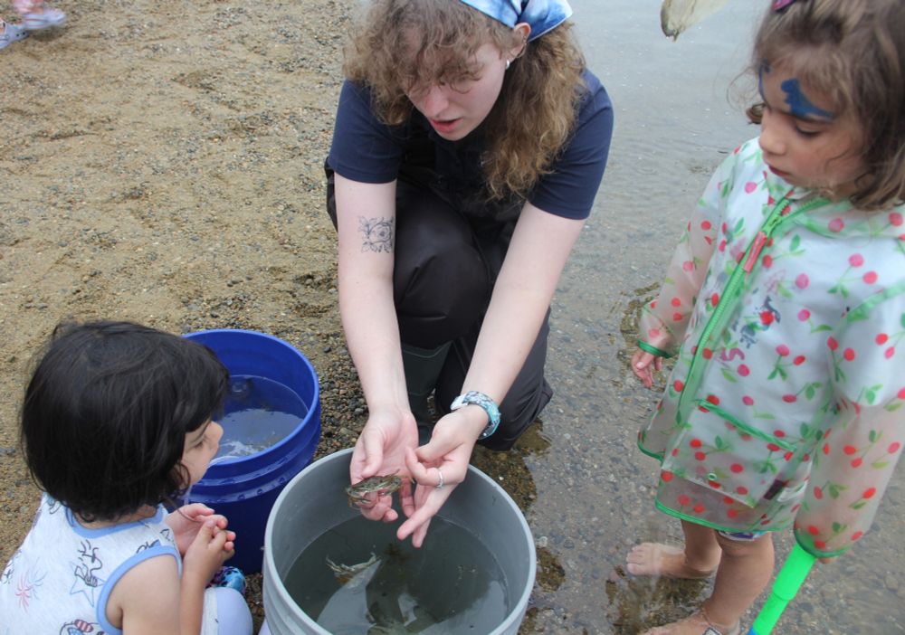 Mystic Aquarium educator showing blue crab to two young girls.