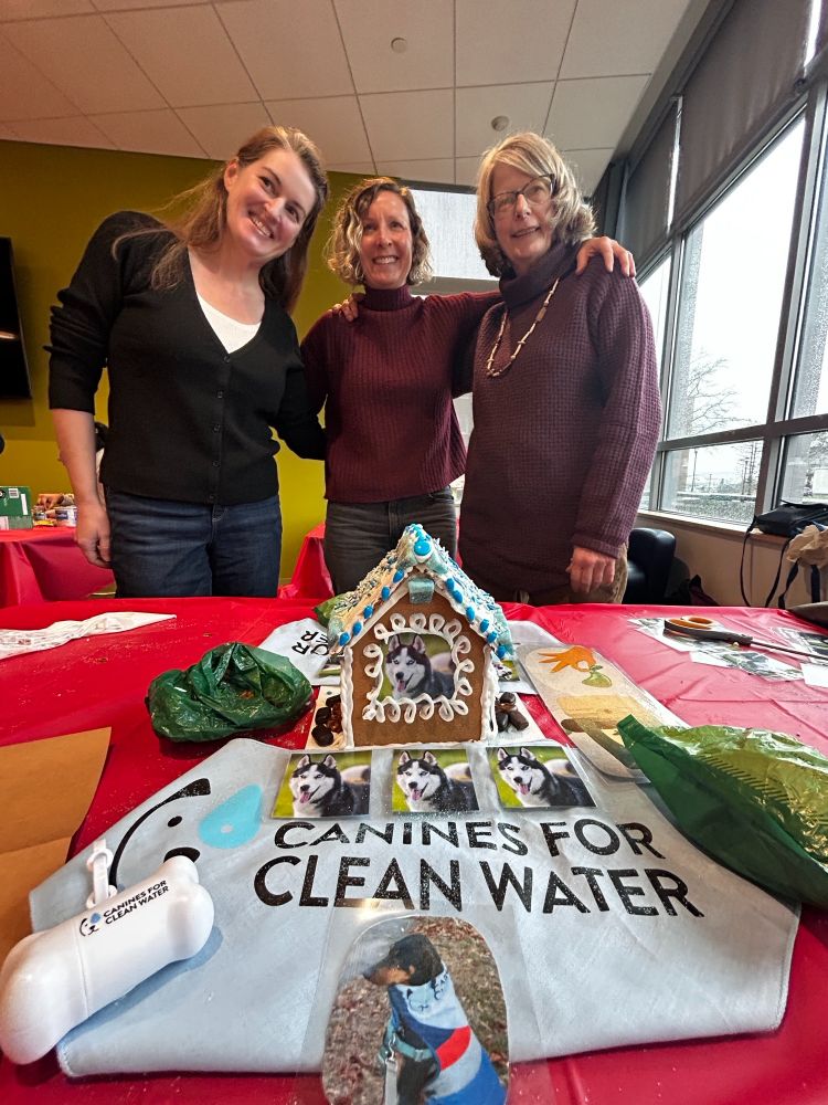 Three CT Sea Grant staff members with "Canines for Clean Water" themed gingerbread house