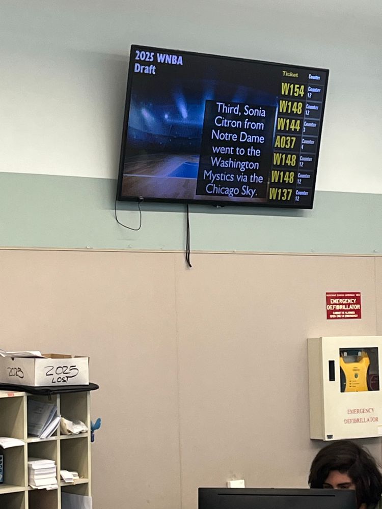 Digital board indicating next in line at the DMV also shows Sonia Citron was the No. 3 draft pick in the WNBA draft as part of the entertainment content