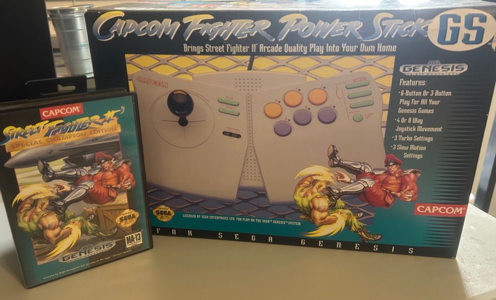 Capcom Fighter Power Stick for Sega Genesis in box with inserts and manual, next to my copy of Street Fighter 2 Special Champion Edition 