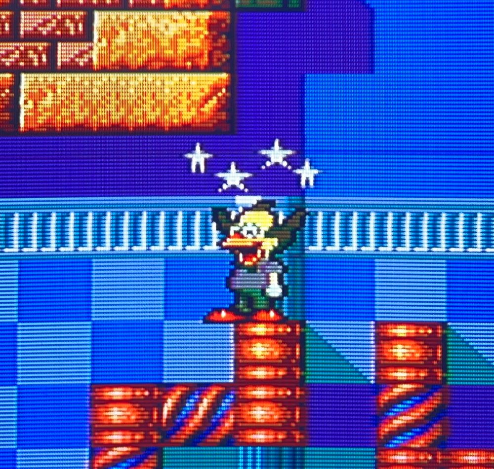 krusty is dizzy with stars around his head but he doesn't seem to mind, maintaining his joyful grin // Krusty's Fun House for Sega Master System, photography on CRT TV 