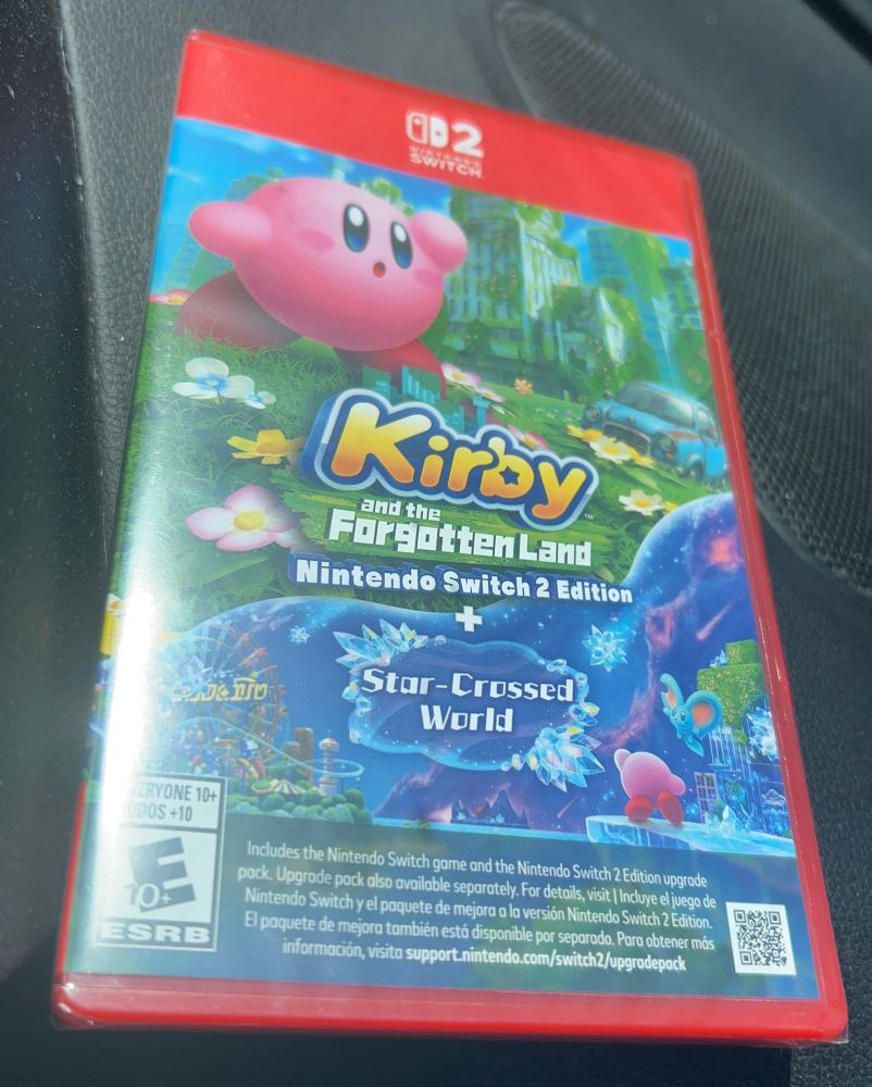a copy of kirby and the forgotten land for Switch 2 sitting on the dashboard of my car 