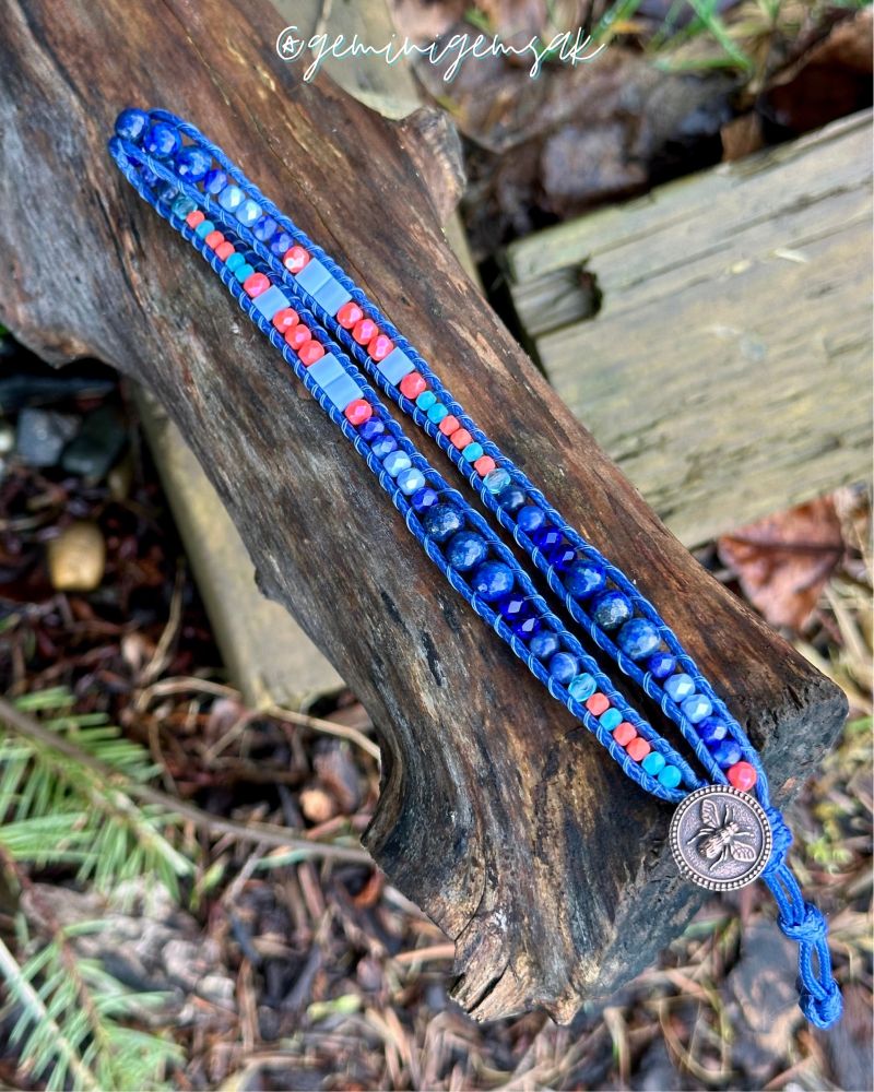 Beaded wrap bracelet made with blue, coral, and teal beads & a bronze button with a bee on it