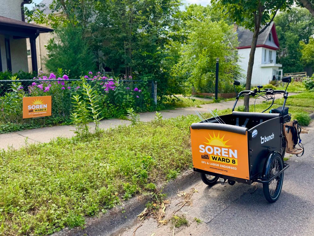 Laura’s bunch bike is parked outside a home with a Soren yard sign. The bike also has a Soren yard sign on the front panel.