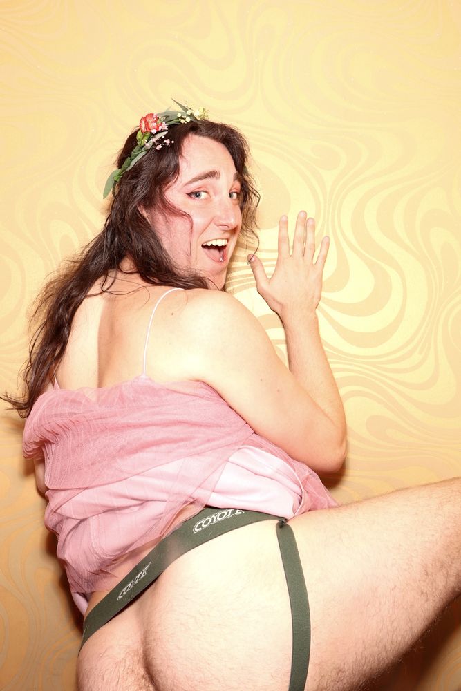 someone in a photobooth has pulled their dress up and turned around to show their hairy ass in a jockstrap to the camera 