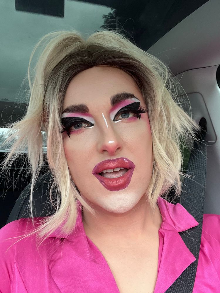 a selfie of a blonde drag queen with bold graphic makeup 