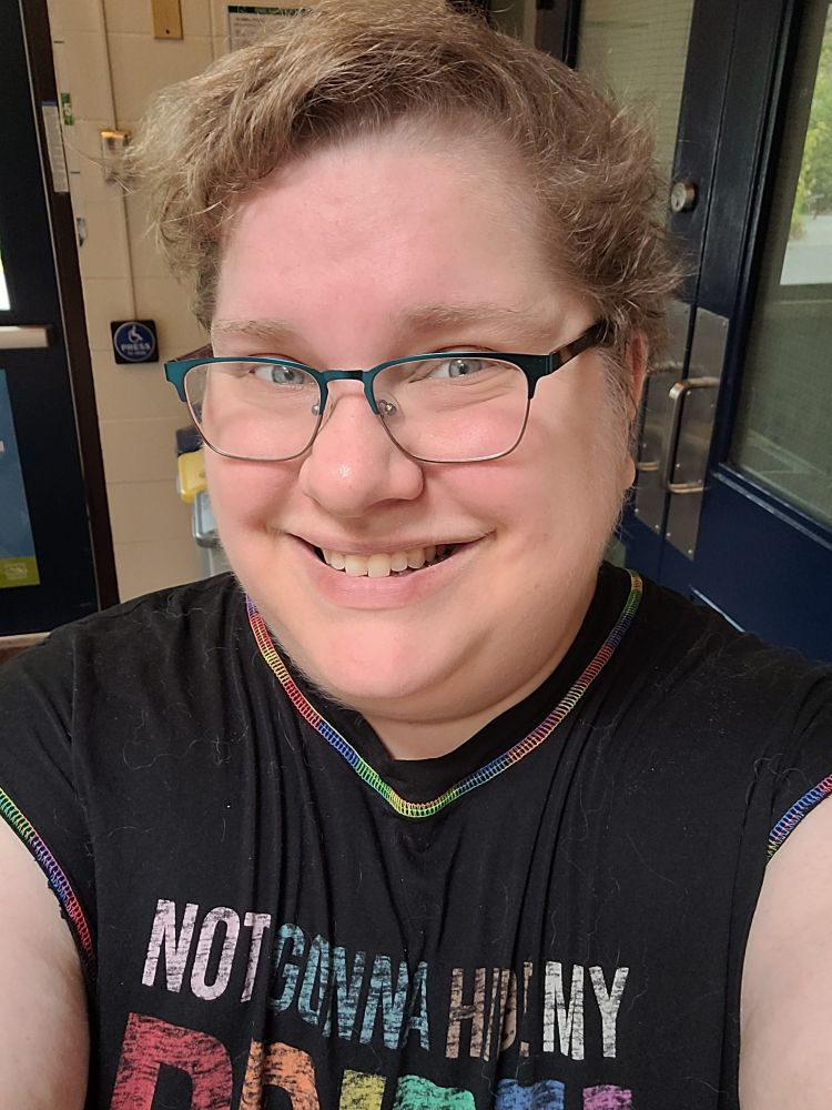 A smiling nonbinary person in glasses