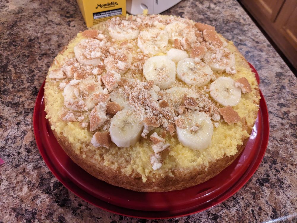 The bottom layer of a banana pudding cake, covered in banana slices, vanilla pudding and crumbled Nilla wafers.