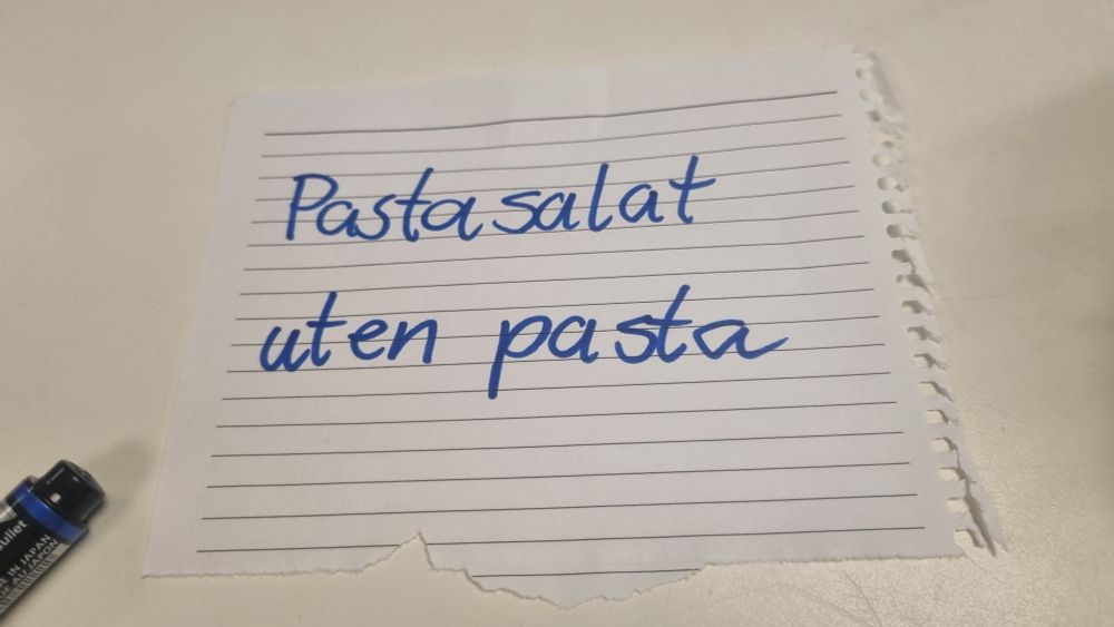 Hvit lapp med teksten "pastasalat uten pasta" i blå håndskrift