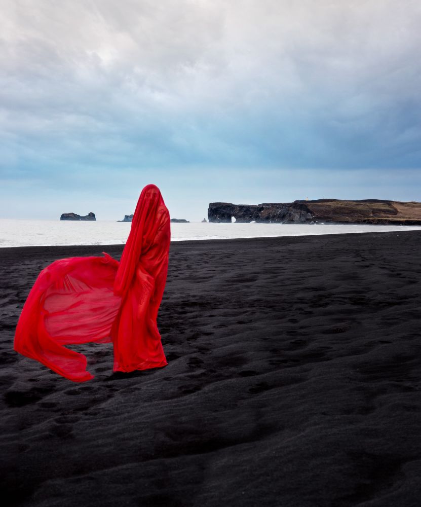Iceland black sand beach with lady draped in red