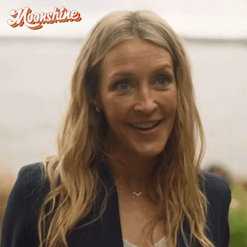 a woman with long blonde hair is smiling with the word moonshine behind her