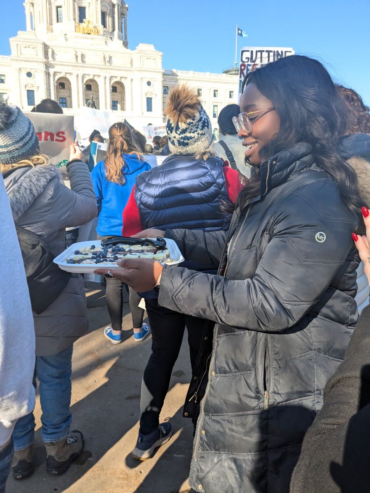 A scientist passes out cheesecake at a rally.