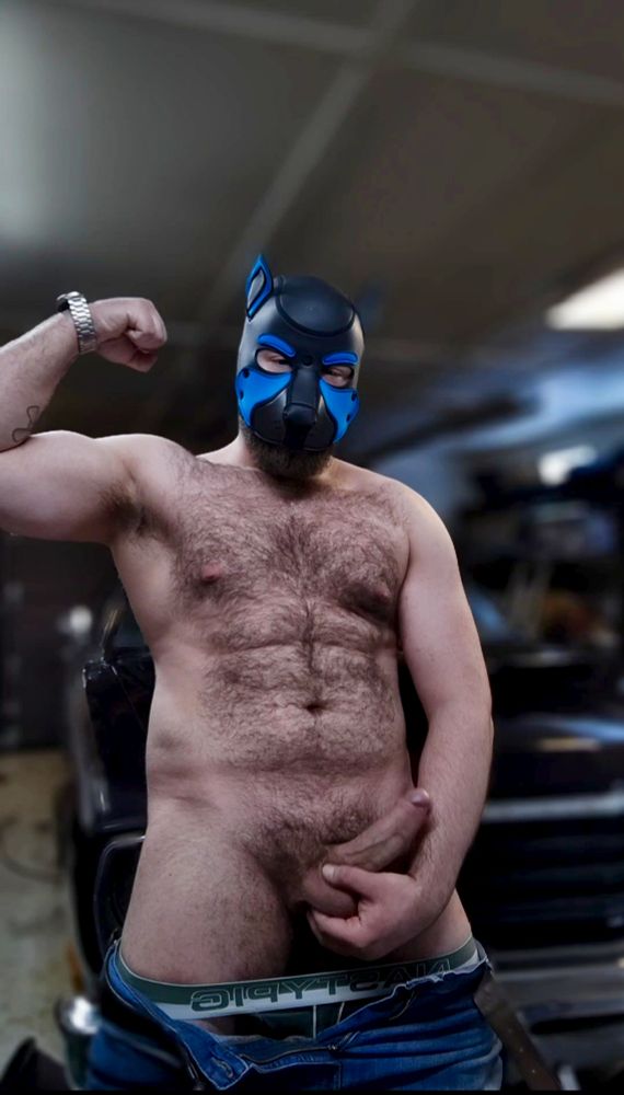 Standing with my pants pulled down. Flexing one arm while supporting my hard cock with the other