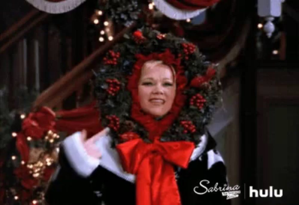 a woman is wearing a christmas wreath around her head .