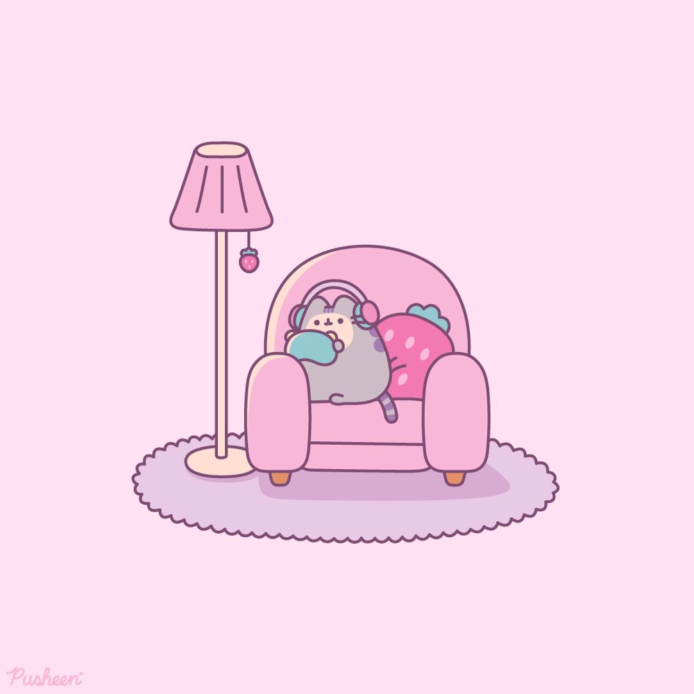 Pusheen is cozy on a pink chair with a strawberry pillow. She is holding a gaming console and wearing headphones.