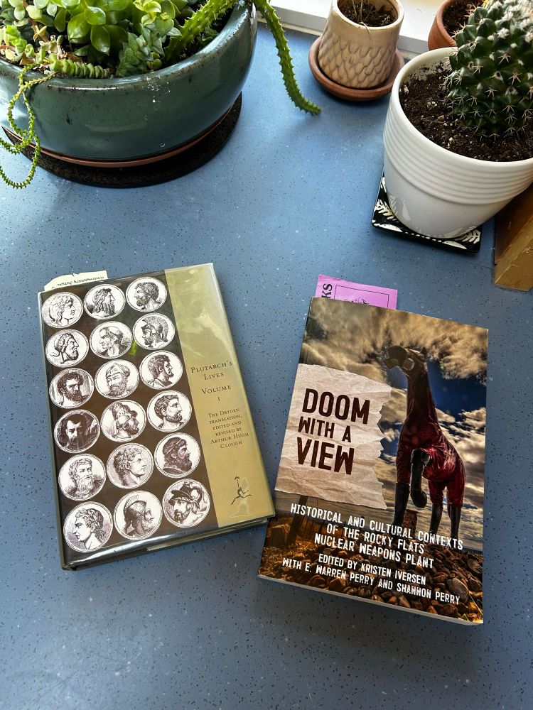 A photo of two books. One on the left Plutarch’s “Lives Volume 1” the book on the right “Doom with a view”