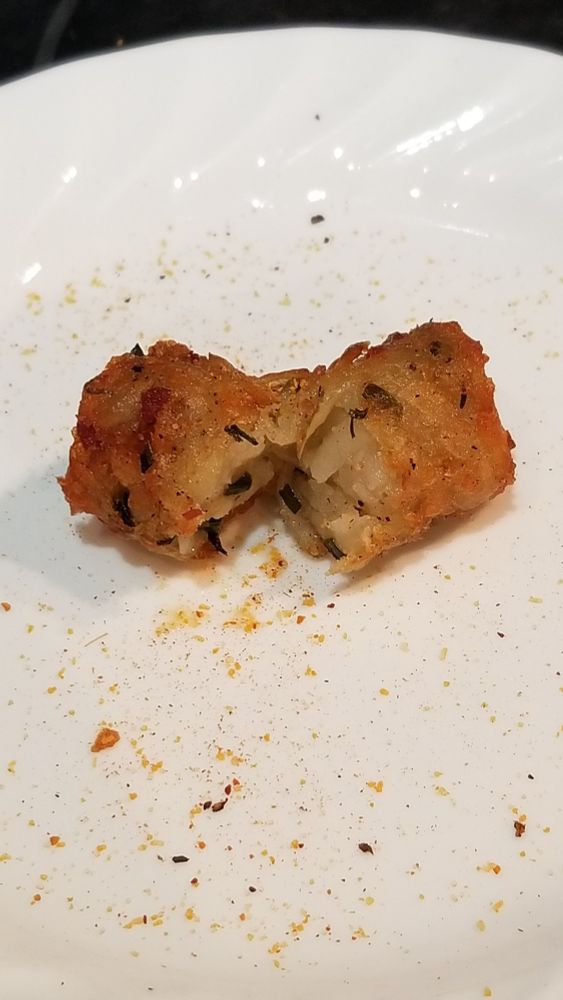 Home made potato tot containing chives and bacon bits on a white plate