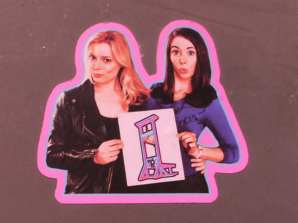 A sticker of Annie and Britta from the TV show "Community" holding an image of a bloody guillotine, outlined in blue and neon pink.  