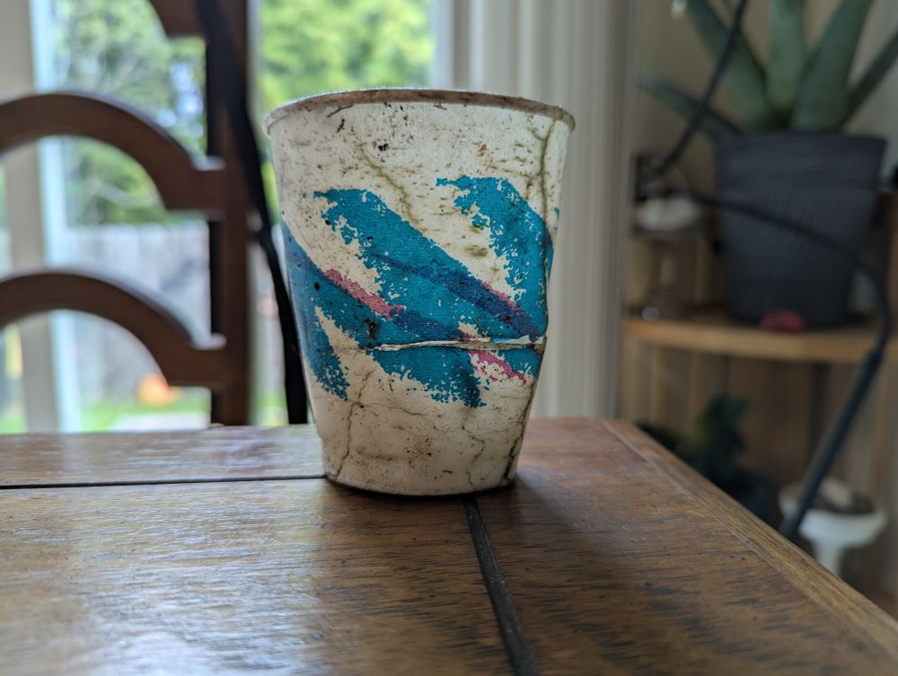 A dirty cracked cup featuring the iconic pink and blue 90s squiggles known as "jazz"