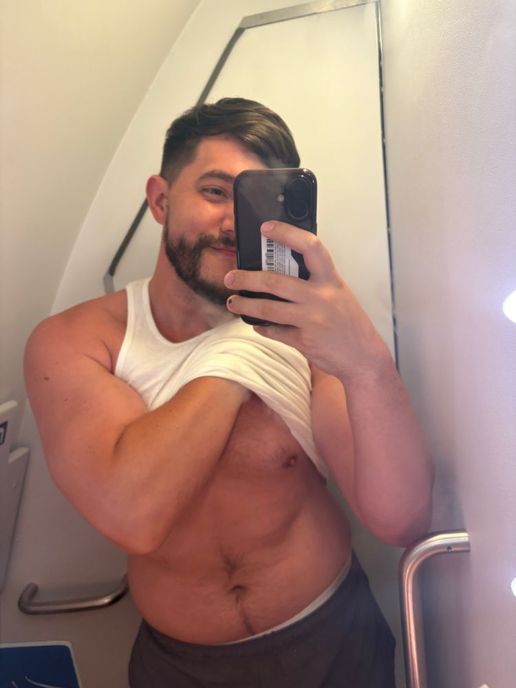 Me in an airplane bathroom lifting up my shirt 