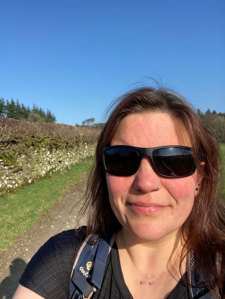 Selfie of a white 40-something woman with dark hair and black sunglasses in a black T-shirt.