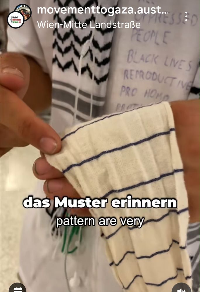 Nun zeigt er ein weißes Tuch in streifenoptik. Es ist weiß und hat ganz dünne, anscheinend blaue oder schwarze Streifen 
 
