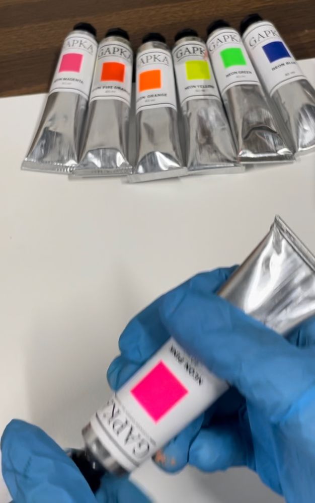 Six new fluorescent oil paint tubes sitting in a row. About to open the 7th to test it out.