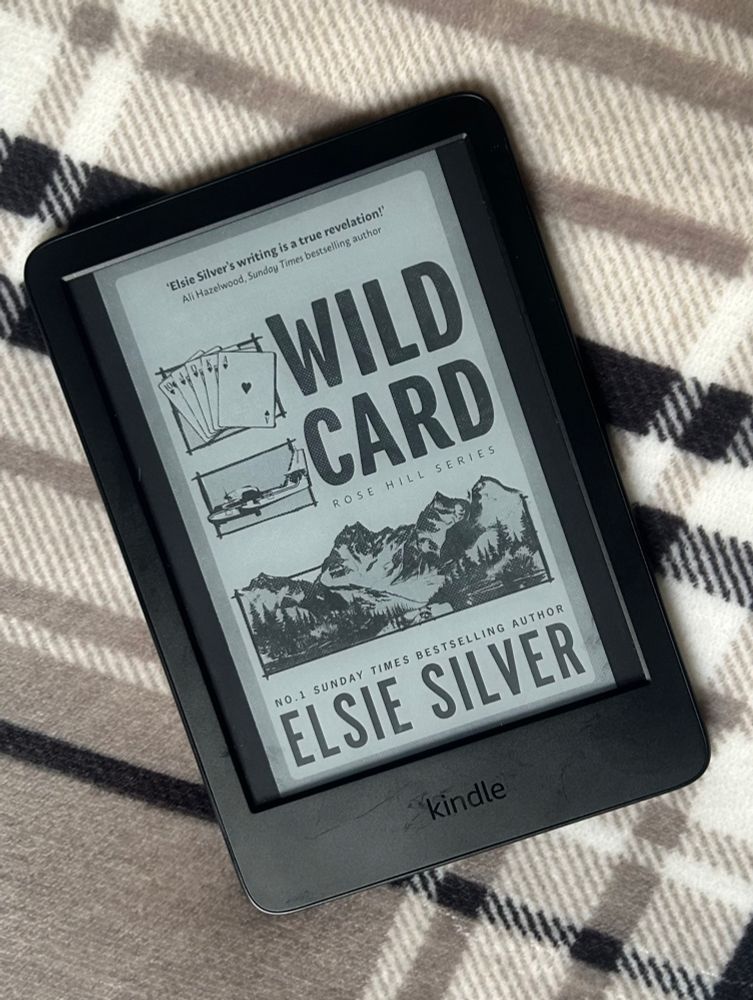 The digital cover of Wild Card, by Elsie Silver, on a kindle screen, over a check background.