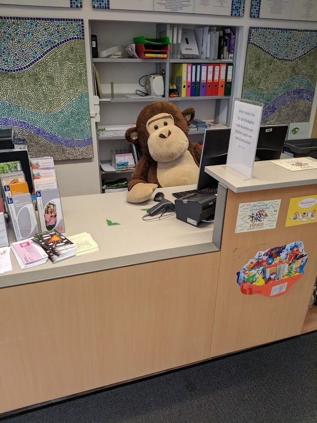 Ein Stoff-Affe sitzt an der Verbuchungstheke einer Bücherei