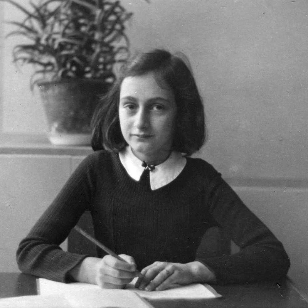 Anne Frank behind a desk writing