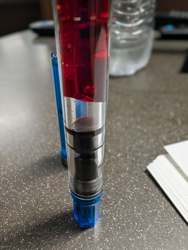 A pen balanced on one end so surface tension keeps the ink from falling down to the bottom of the container.