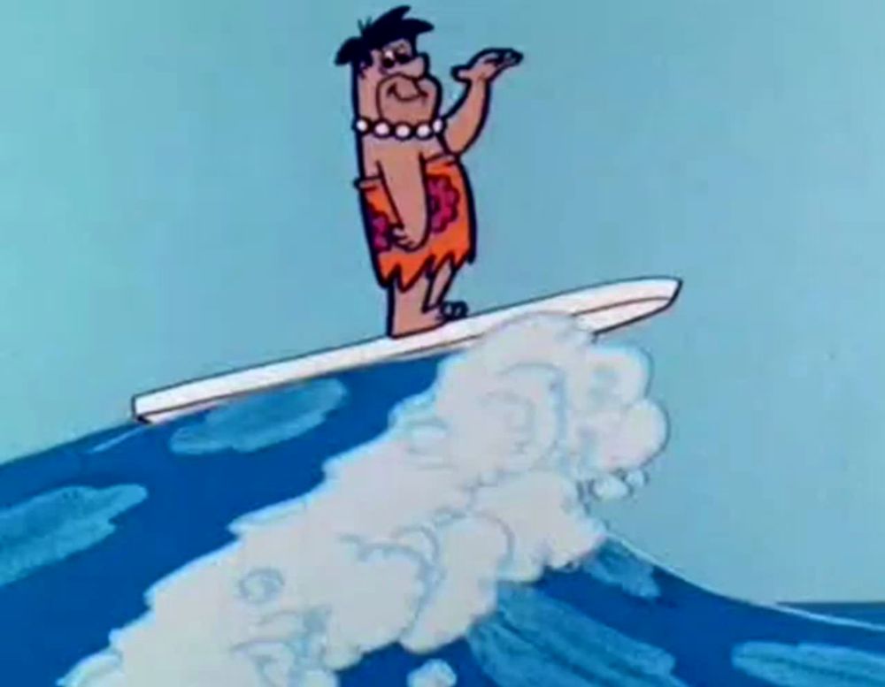 flintstone is riding a wave on a surfboard in the ocean .