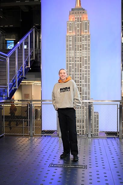 Paige Bueckers in a gray wnba hoodie in front of a picture of the Empire State Building 