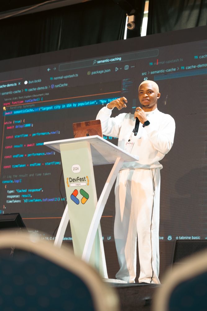 Tobiloba on stage holding a microphone speaking to the audience 