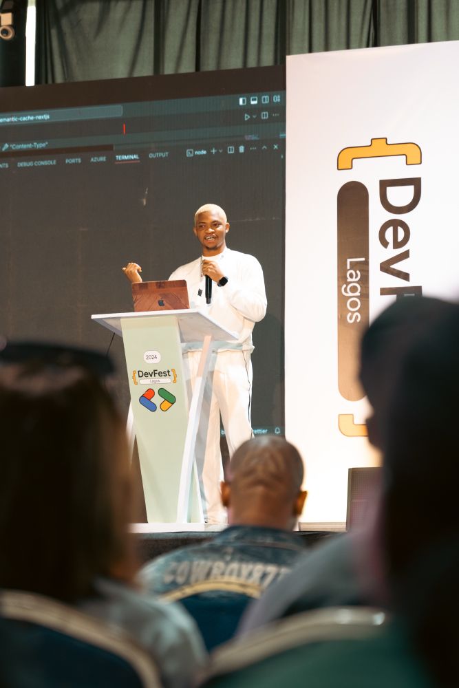 Tobiloba on stage holding a microphone speaking to the audience 