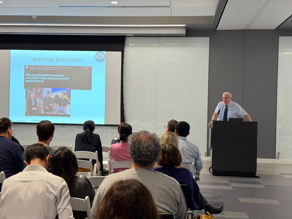 Dr. Jeremy Berg is presenting from a lectern in front of an audience of vision researcher scientists. 