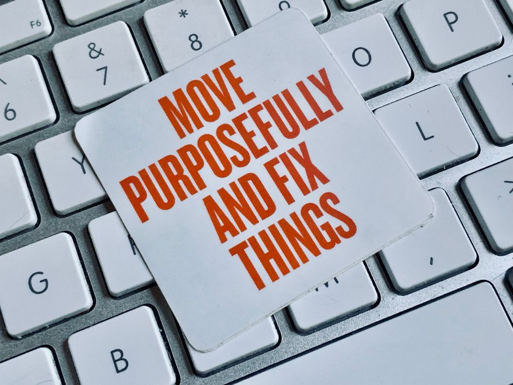 A sticker on a keyboard that says move purposefully and fix things.